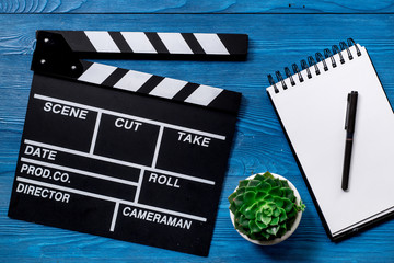 Work table of producer. Movie clapperboard and notebook on blue wooden table background top view