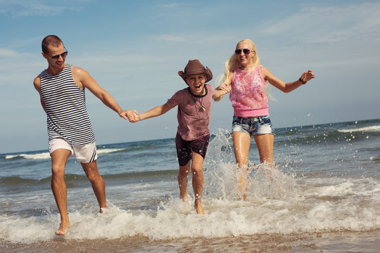 Happy young family having fun running on beach. Family traveling concept