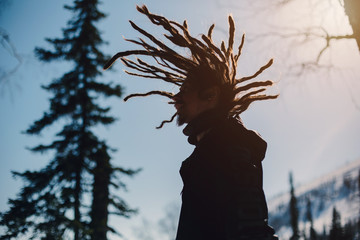 Happy man silhouette with windy dreadlocks in winter mountain forest