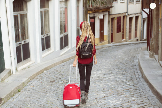 Traveling female walking with suitcase on  European city street, tourism in Europe, travel background