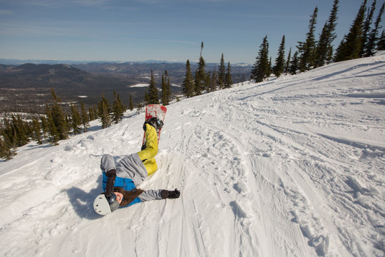 Happy Female snowboarder lying on the snow on mountain top. Winter sport, snowboard freeride