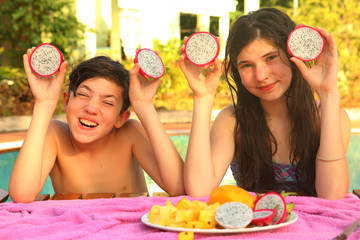 kids siblings in tropical pool outdoor resort with dragon fruit cut close up photo