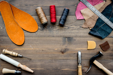 Working place of shoemaker. Skin and tools on brown wooden desk background top view copypace - obrazy, fototapety, plakaty
