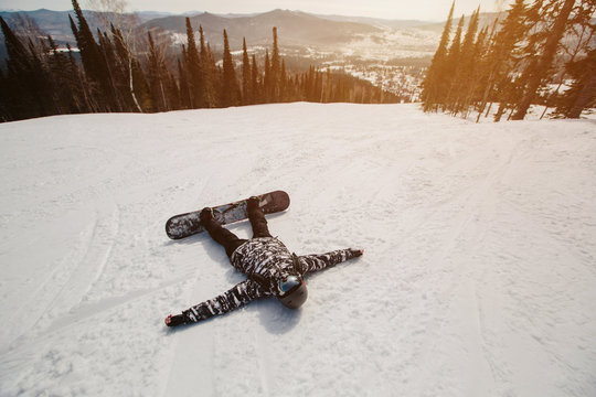 Portrait of snowboarder lying on snow skiing track. Enjoy, relaxation, winter sport, mountain freeride in Siberia