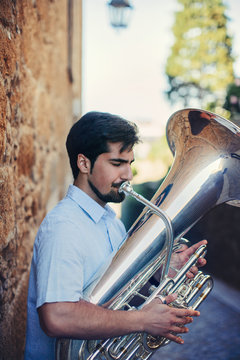 Close view portrait of  Street musician playing tuba outdoor in European city