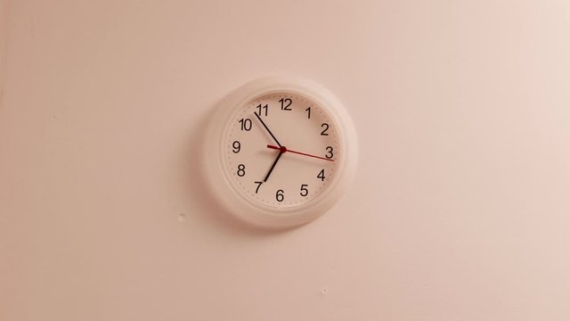 Nobody. White clock on wall ticking showing seven hours, time lapse 4K