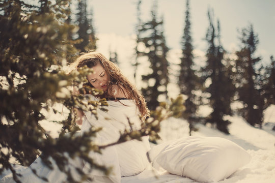 Portrait of beautiful woman with long brown hair sitting on the snow bad