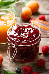 Tasty fruit red strawberry berry jams in glass jar with fruits on wooden table. Closeup.