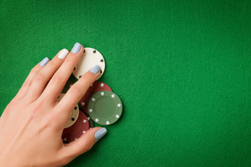 Woman hand holding poker chips on green casino felt background