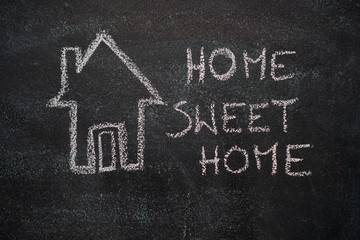 Fototapeta premium House with home sweet home writing drawn with white chalk on blackboard