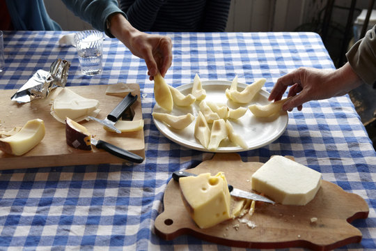 Two people taking cheese from plate