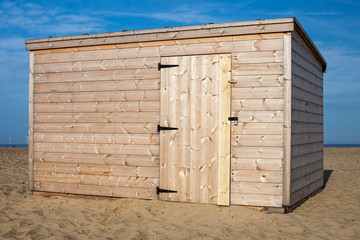 New pinewood shed on the beach. Unpainted storage hut.