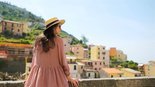 Young woman with beautiful view at old village Riomaggiore, Cinque Terre, Liguria, Italy. European italian vacation.