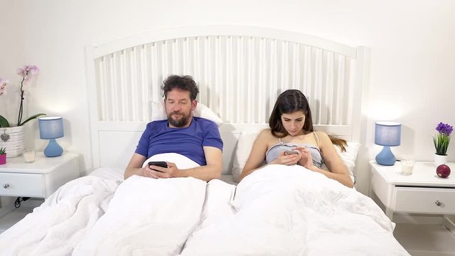 Modern times couple in bed not talking occupied with social network no love