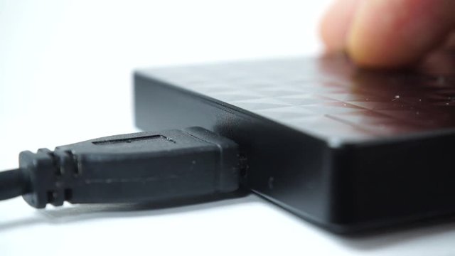 Details of male hand pushing usb cable plug into usb slot on hard external disk 4K ProRes HQ codec