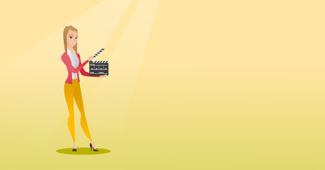 Smiling woman holding an open clapperboard.