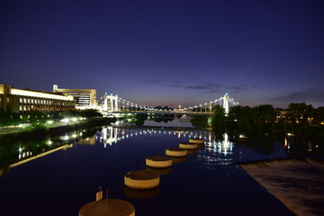 Fototapeta na wymiar Lighted suspension bridge over river at night