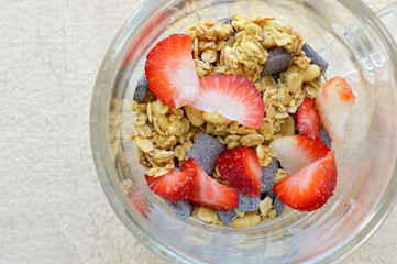 Closeup of a Glass cup filled with granola, strawberry and chocolate drops