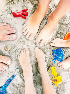 Happy family feet on the beach playing with toys in sand