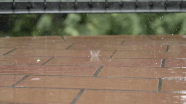 Raindrops falling on balcony floor in slow motion