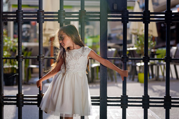 Obraz na płótnie Canvas A little sweet girl in a white dress and wearing sunglasses.