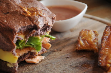 knife on hamburger and french fries on the wooden plate, focus at hamburger