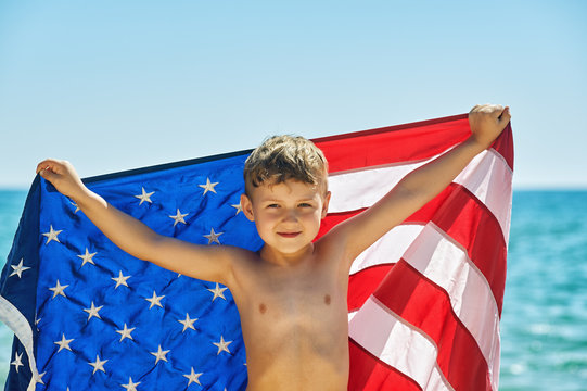 The boy with the flag of America on the sea shore