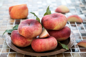 Plattpfirsiche gestapelt auf einem Kupferteller 