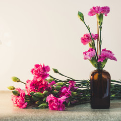 Bright pink carnations flower in the japanese glass vase on table . Vintge image style