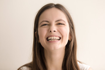 Headshot portrait of laughing young woman. Cheerful teen girl with happy facial expression looking at camera with toothy smile. Female positive emotion, comic situation concept. Close up. Front view