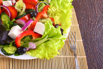 salad from fresh vegetables in a plate on a table, selective focus