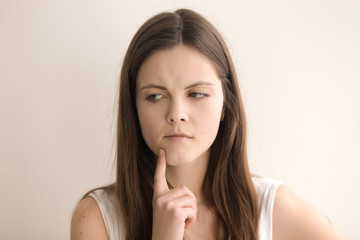 Naklejka premium Headshot portrait of thoughtful young woman. Lovely teen girl deeply immersed in thoughts, thinking about problem solving. Pensive female tensely ponders difficult question. Close up. Front view