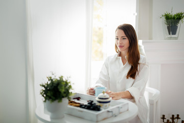 Young woman with cup of coffee sitting at table