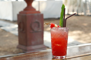 A glass of fresh watermelon juice with sliced watermelon and culantro on wooden table, Healthy drink for summer concept.