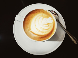 Cup of coffee latte and coffee spoon isolated on black color background