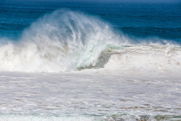 blue wave crashes down at the beach in El Cotillo village in Fuerteventura island, Spain