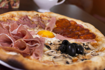 Hot pizza slice with melting cheese on a rustic wooden table. Fresh pizza with tomatoes, cheese and mushrooms on wooden table close up.