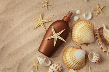 Fototapeta na wymiar suntan lotion and seashells on the sand beach
