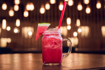 Watermelon cocktail on burning light bulbs background