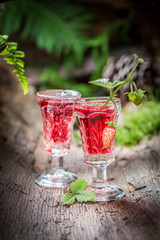 Sweet liqueur with wild strawberry and alcohol in forest
