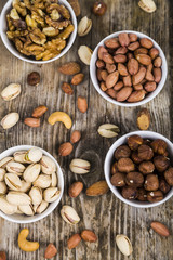 Four bowls with nuts on a  wooden table