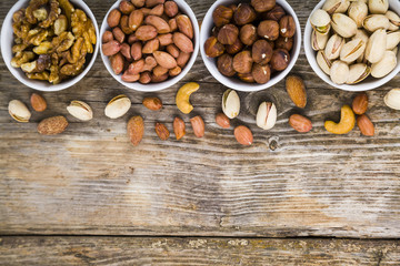Four bowls with nuts on a  wooden table