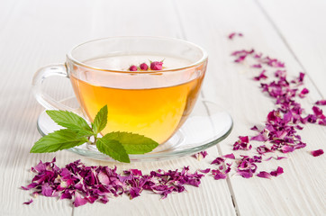 Rose tea and dried petals on white wooden table