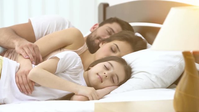 The cute family sleeping on the bed