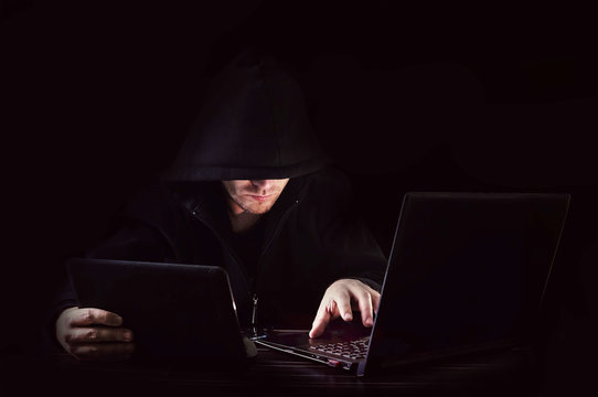 Cyber attack with unrecognizable hooded hacker