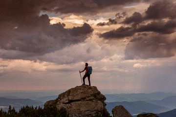 Trekker hiking on a mountain with beautiful storm clouds in background