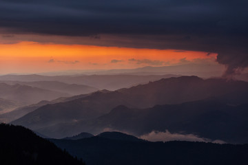 Beautiful sunset over mountains with storm clouds in background. Masivul Ceahlau, Romania.