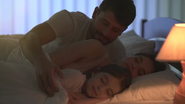 The caring man sleeping on the bed with his family. night time