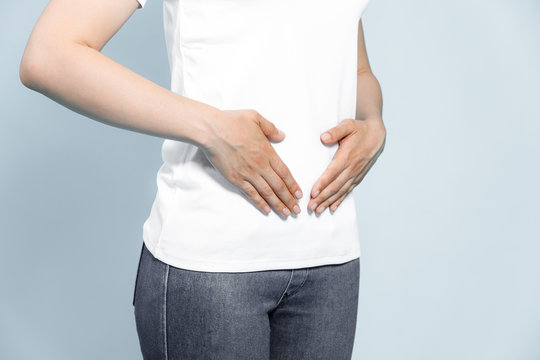 Young woman hand holding her stomach on a white background
