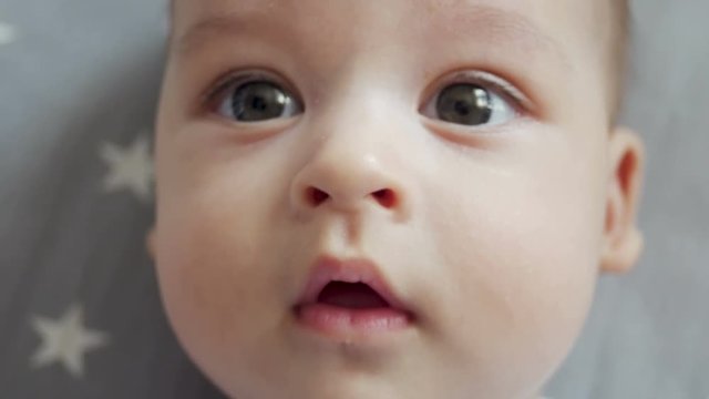 infant lies on back with open big eyes